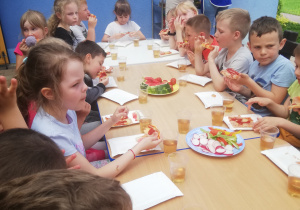 dzieci jedzą owoce i warzywa oraz pizzę